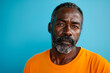 African American middle-aged man exudes athleticism and seriousness against a vibrant light blue backdrop in striking portrait.
