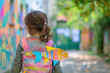 Girl with colorful paper fish attached to her back in the yard of French school. Attaching paper fish to someone's back is a common April fools day joke in France.