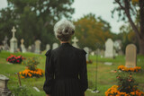 Fototapeta Boho - Sad senior woman grieving her loss on a cemetery. Lonely widowed wife by the headstone of her spouse