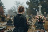 Fototapeta Boho - Sad young woman grieving her loss on a cemetery. Lonely widowed wife by the headstone of her spouse.