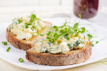 Delicious toast with pate boiled egg, cucumber and cream cheese on a white plate. Healthy eating, breakfast. Keto diet food. Tasty food.