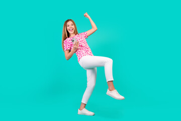 Sticker - Full length photo of lovely teen lady hold device raise fist win lottery wear trendy print pink garment isolated on cyan color background