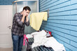 A young man dries clothes on a dryer after washing in the bathroom. Caring husband doing housework