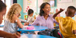 © Monkey Business - Female Primary Or Elementary School Teacher Gives Student High Five At Desk In Multi-Cultural Class