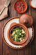 delicious gourmet meal served in a rustic clay pot, garnished with fresh herbs, presented on a wooden table setting.