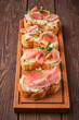 gourmet ham and cream cheese canapés on wooden board