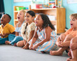 © Monkey Business - Line Of Smiling Primary Or Elementary School Students Sitting On Floor During Classroom Lesson