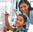 © Monkey Business - Portrait Of Primary Or Elementary School Student With Teacher Writing On Whiteboard In Lesson