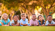 © Monkey Business - Portrait Of Multi-Cultural Primary Or Elementary School Student Friends Lying On Grass Outdoors