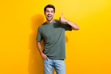 Poster - Portrait of funny ecstatic guy with stubble wear stylish t-shirt show thumb up nice job arm in pocket isolated on yellow color background