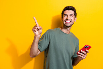 Poster - Portrait of intelligent guy wear stylish t-shirt hold smartphone look directing at sale empty space isolated on yellow color background