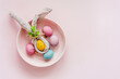 Ein Osterei mit einer Stoffserviette als Hasenohren und bunte Eier in einer Schüssel. Draufsicht, Humor.