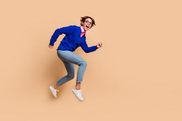 Poster - Full size profile portrait of impressed cheerful girl jump rush empty space isolated on beige color background