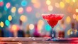 A red margarita in a martini glass with a salted rim on a wooden against a bokeh background