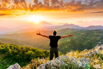 happy man watching amazing highland evening sunset, person delight with nature landscape