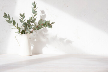 Sticker - Close-up of wooden table with eucalyptus twigs in vase and light shadows