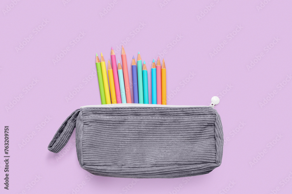 Case with colorful pencils on lilac background
