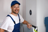 Fototapeta Mapy - smiling maintenance and repair service worker working with house gas heating boiler