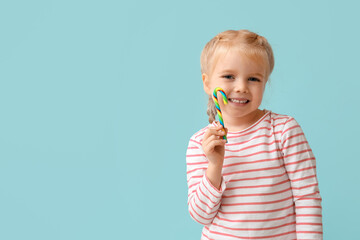 Wall Mural - Cute little girl with colorful candy cane on blue background