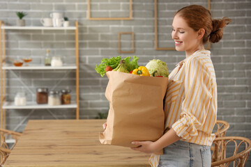 Wall Mural - Young woman with paper bag of healthy food in kitchen