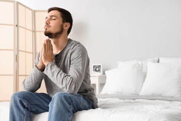 Wall Mural - Young man praying in bedroom