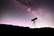 Silhouette of a telescope  standing on the hill, on the milky way galaxy background.