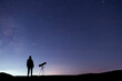 Silhouette of a hiker with telescope  standing on the hill, on the milky way galaxy background.