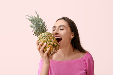 Poster - Beautiful young woman with tasty pineapple on pink background