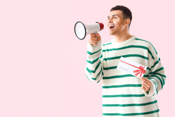 Canvas Print - Young man with gift card shouting into megaphone on pink background