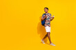 © deagreez - Full length photo of positive man wearing casual summer outfit bring phone and backpack look copyspace isolated on yellow color background