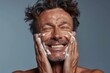 © Jennie Pavl - A handsome man takes care of his skin with a gentle facial cleanser, highlighting the importance of self-care. His happy expression shows the joy of pampering himself.