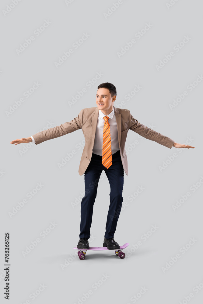 Funny businessman with skateboard on light background