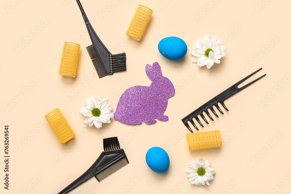 Paper bunny with Easter eggs, hairdressing accessories and daisies on beige background