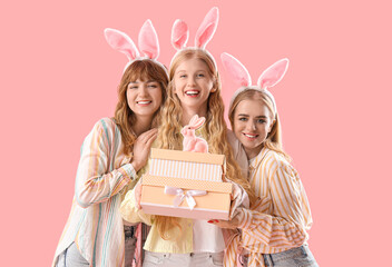 Poster - Young girls with Easter bunny ears and gifts on pink background