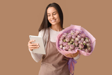 Sticker - Young delivery woman with bouquet of beautiful roses and modern tablet computer on brown background