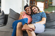 A diverse couple is sharing a cozy moment on a sofa at home