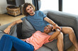 A diverse couple relaxes comfortably on a gray sofa at home