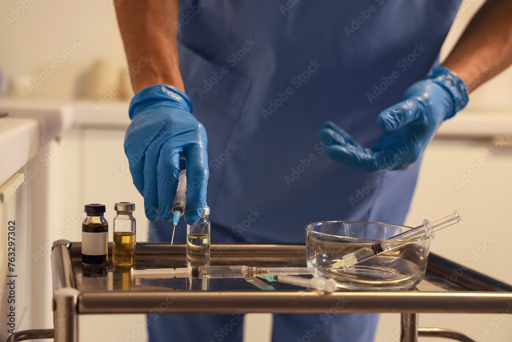 Male nurse with ampule and syringe working evening shift in clinic