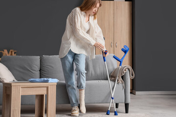 Canvas Print - Injured young woman with crutch after accident walking at home