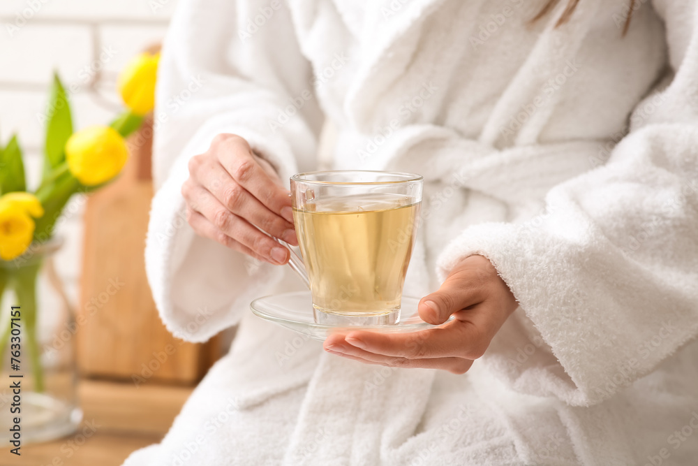 Young woman drinking green tea in kitchen