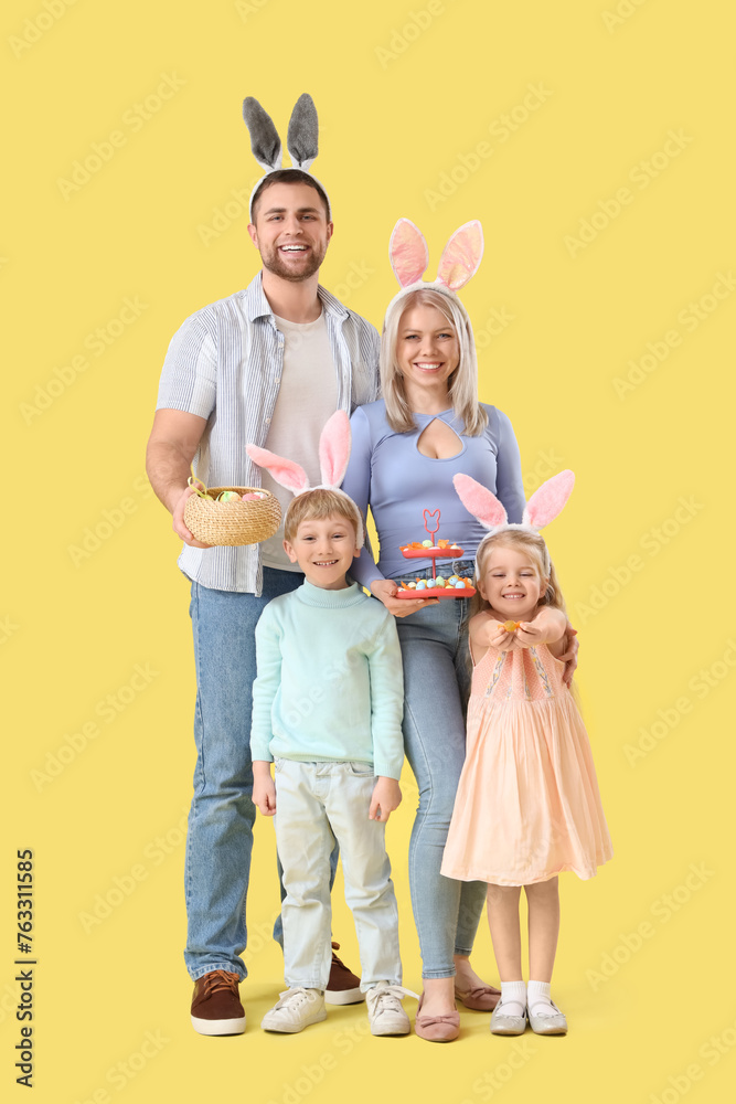Happy family in bunny ears with Easter eggs on yellow background