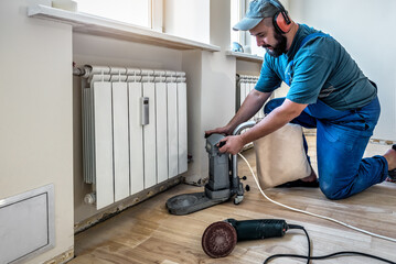 Wall Mural - Worker with professional orbital sander for grinding cleaning parquet floor for difficult place