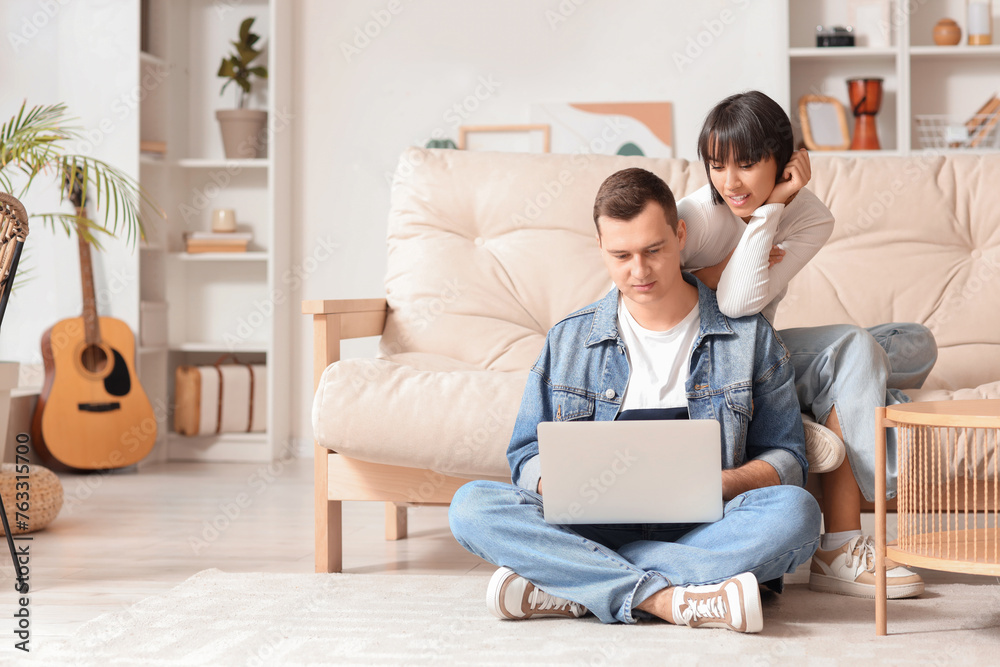 Young couple in love using laptop at home