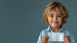 © Fxquadro - Smiling child with tousled blond hair in a denim shirt presenting a white card, against a neutral background