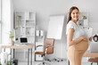 © Pixel-Shot - Young pregnant businesswoman with clipboard in office
