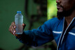 © KANGWANS - A man holding a bottle of water. The bottle is clear and has a blue cap