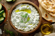 Overhead View Tzatziki with Fresh Ingredients. Overhead shot of tzatziki in a bowl with cucumbers and naan, fit for recipe sites.