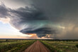 Dirt road leading to supercell storm clouds