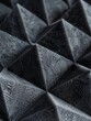 A macro close up picture of a acoustic anti noise foam, egg tray shaped and triangles pyramids in black color. AI Generated.