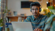 © Muhammad - Indian young man wearing a headset conducts a webinar, online conference sitting at a laptop in the office